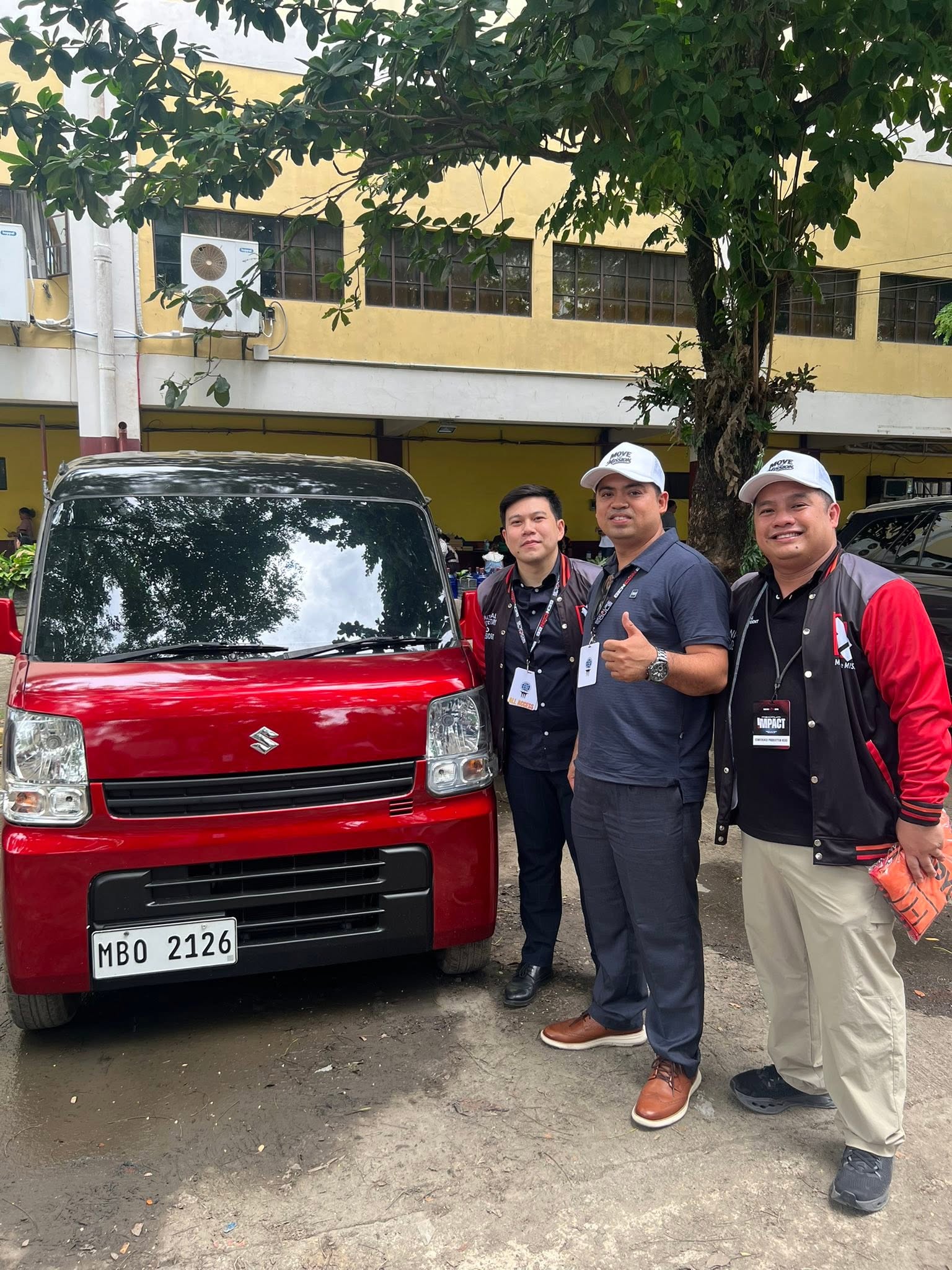 Three ministers including Ptr. Joseph Carino posing beside the red Suzuki Multicab after the raffle draw